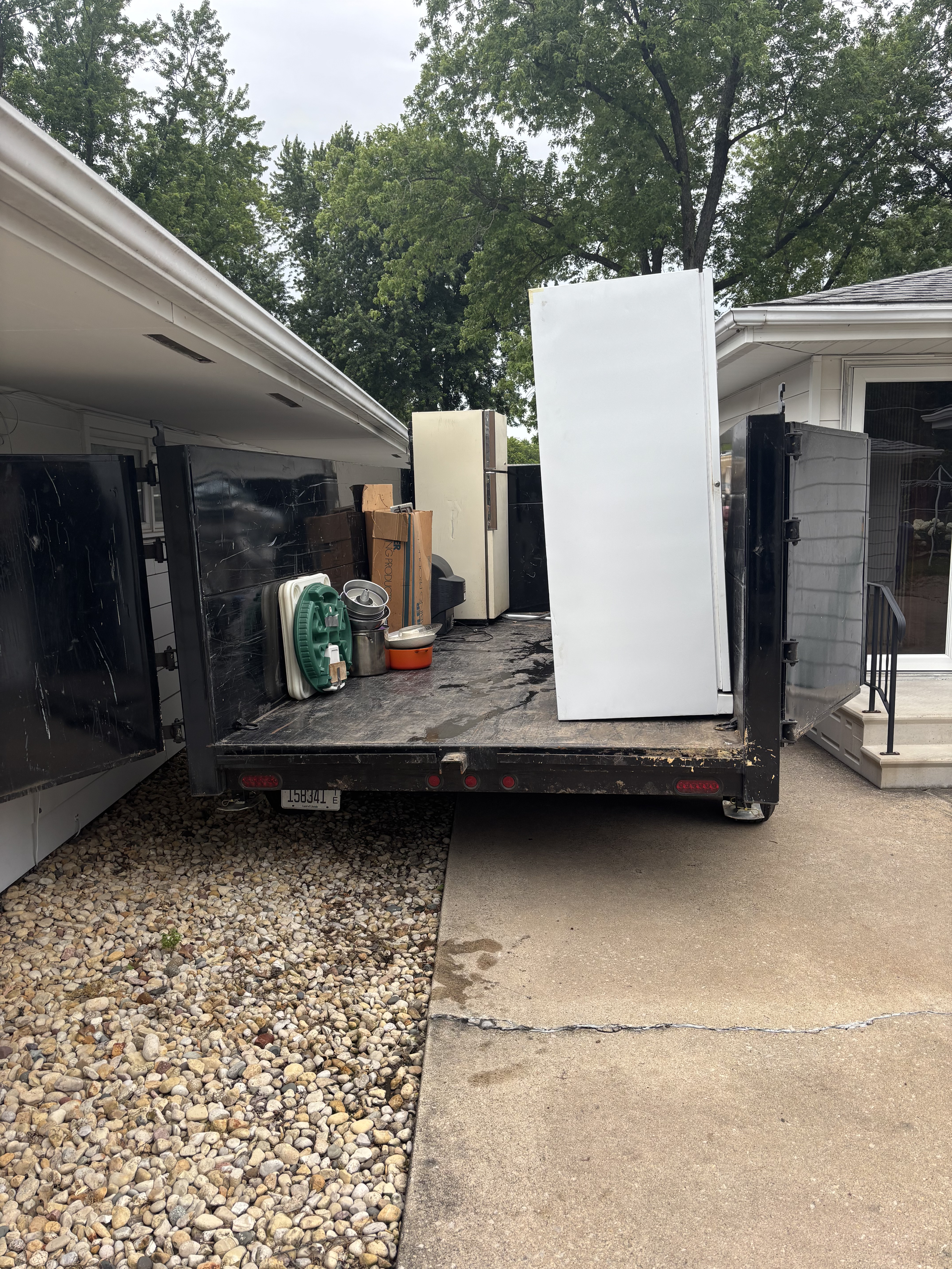 Fridge and appliances loaded on trailer at suburban driveway