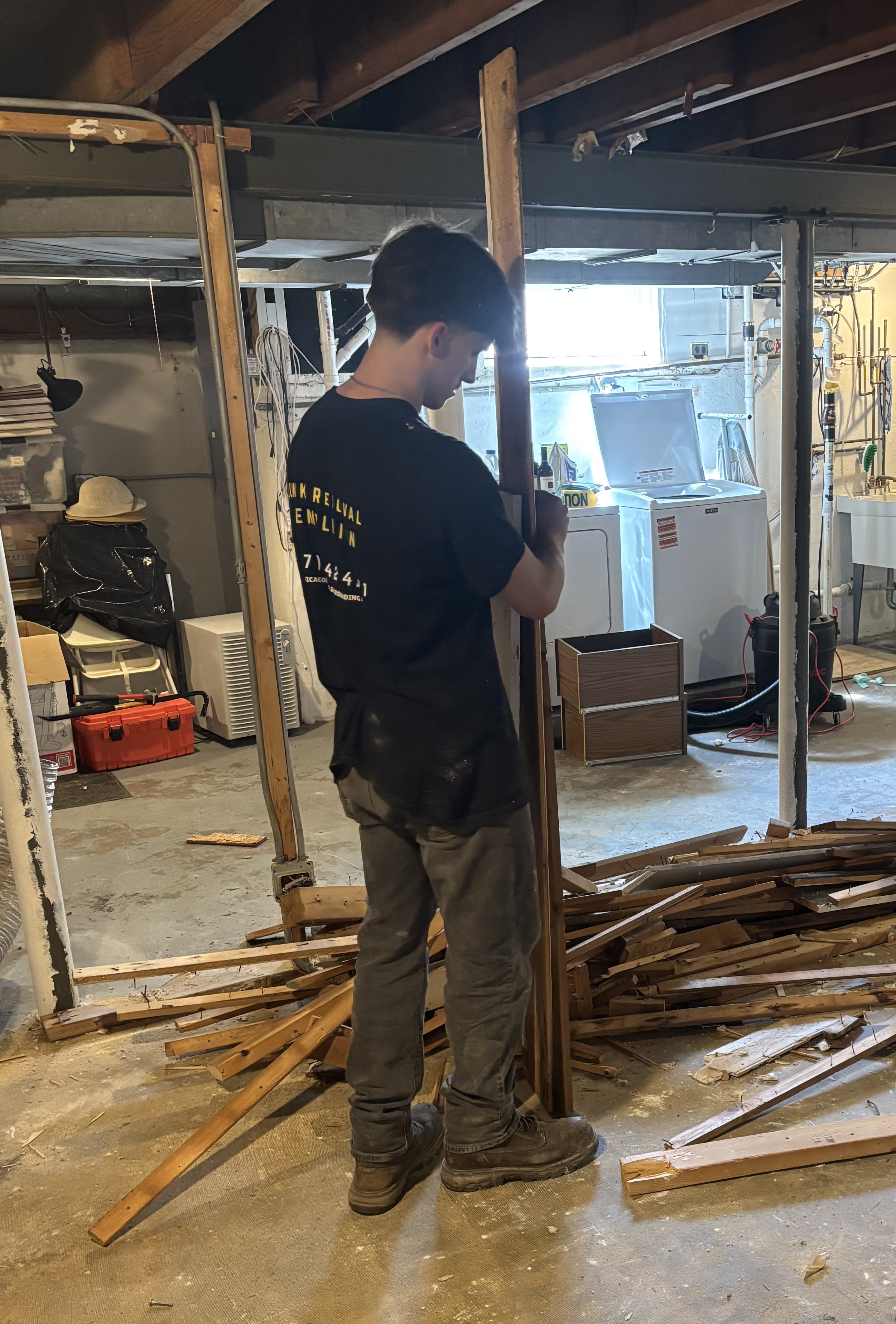 Worker removing wood framing during basement demolition