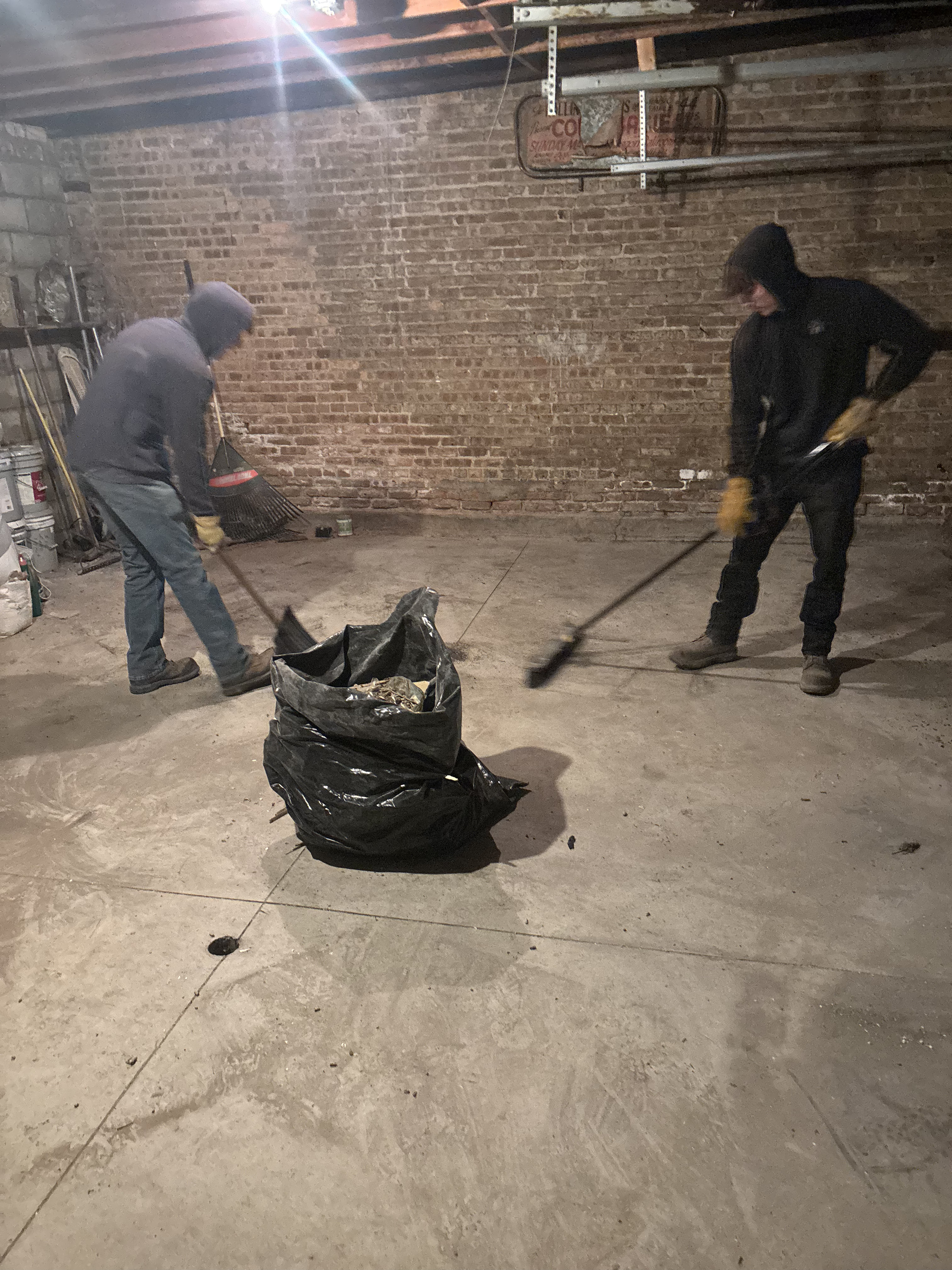 Two workers sweeping out a fully cleared basement
