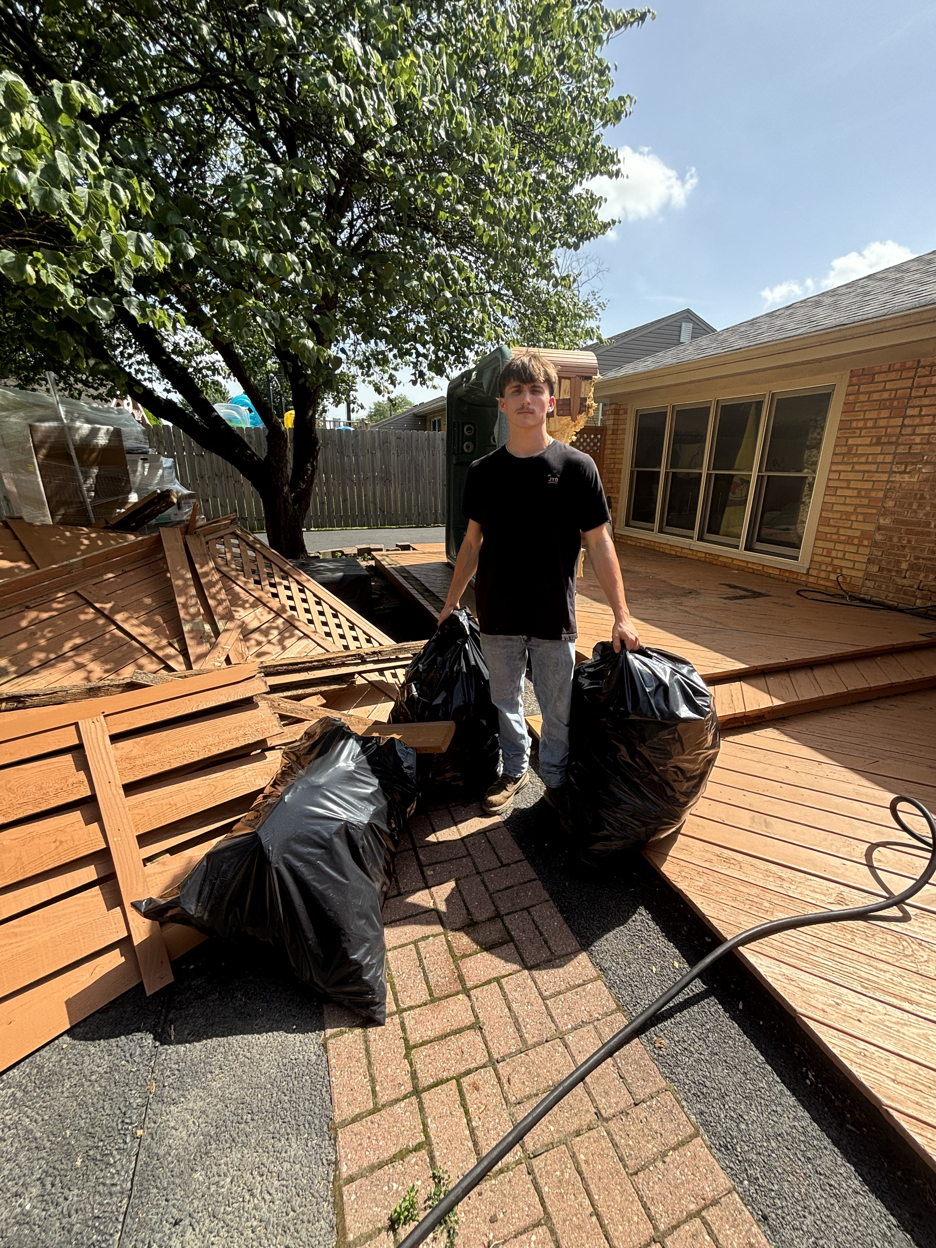 Worker hauling garbage bags off a deck during demolition