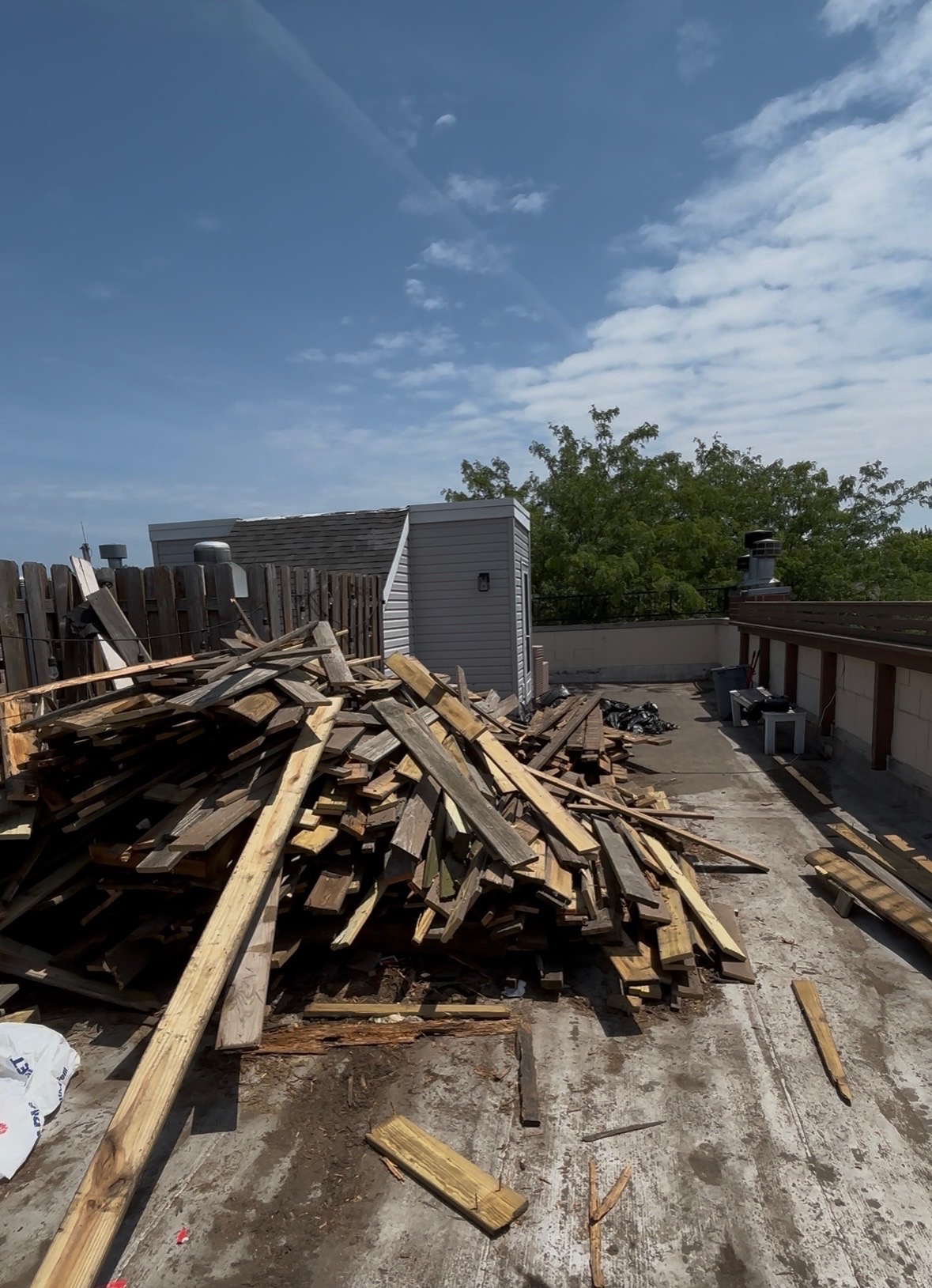Massive lumber pile from rooftop deck demolition ready for removal
