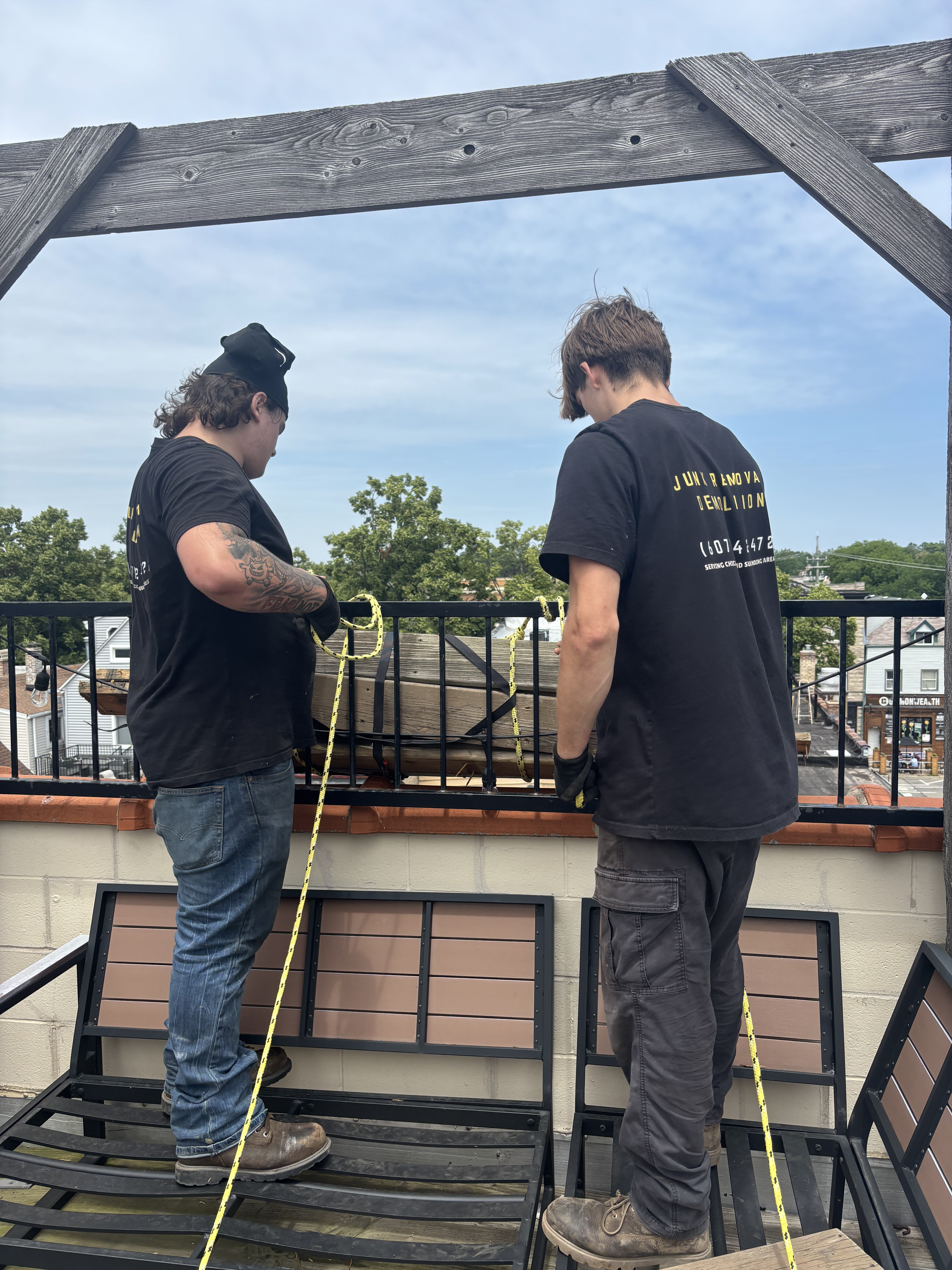 Brothers dismantling a rooftop pergola structure