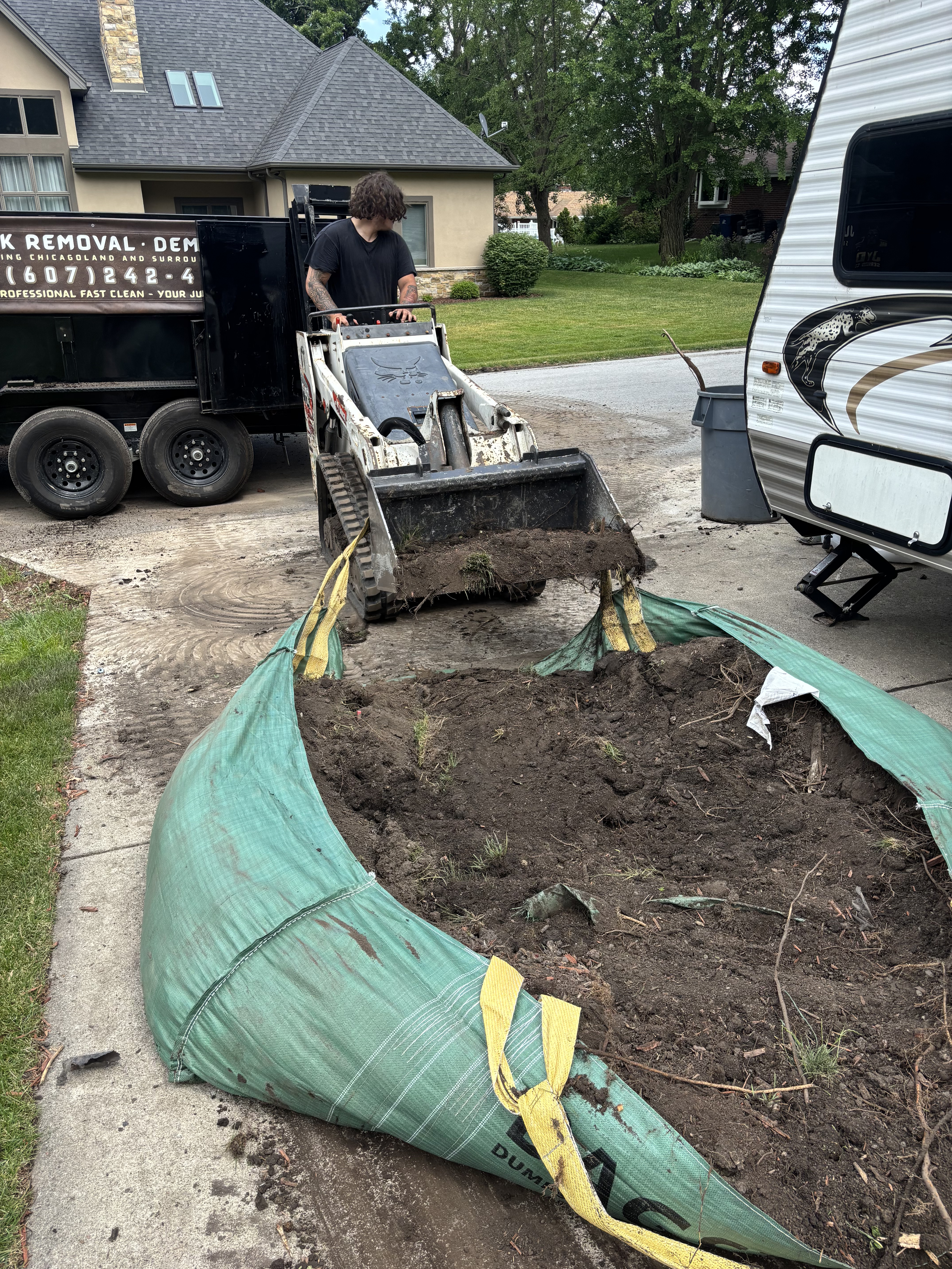 Mini skid steer loading soil into bags at suburban job site