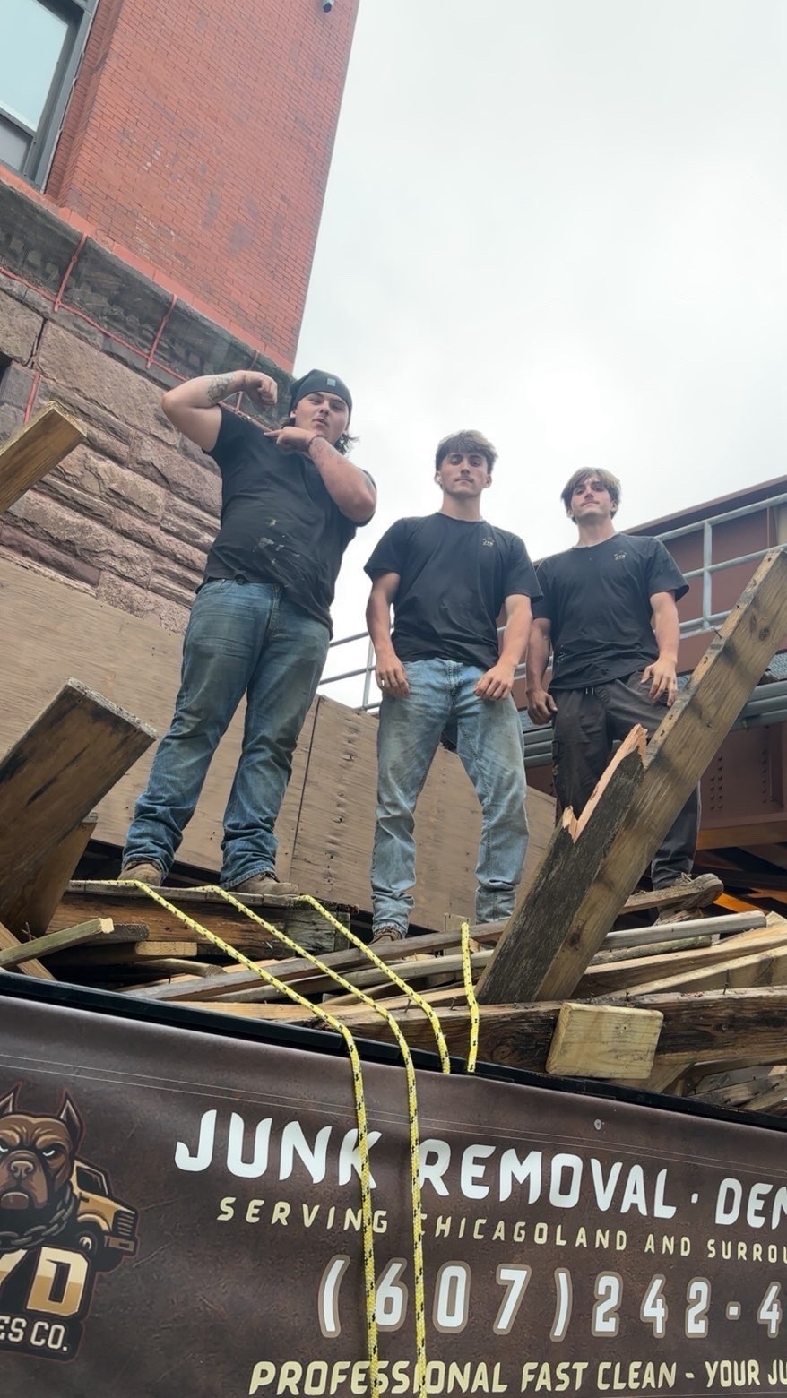 Three crew members standing atop rooftop demolition debris