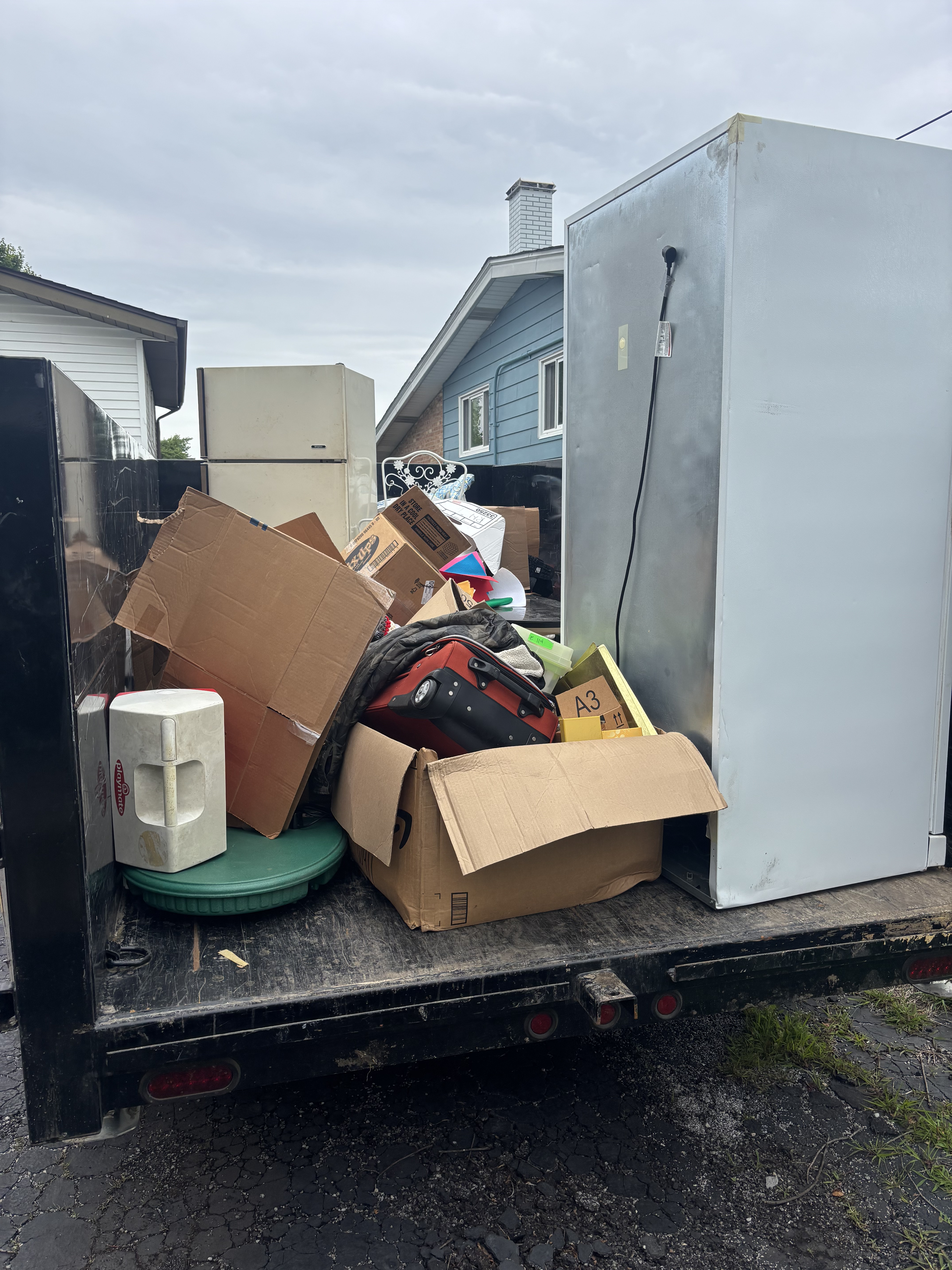 Truck loaded with mixed junk haul including boxes and appliances